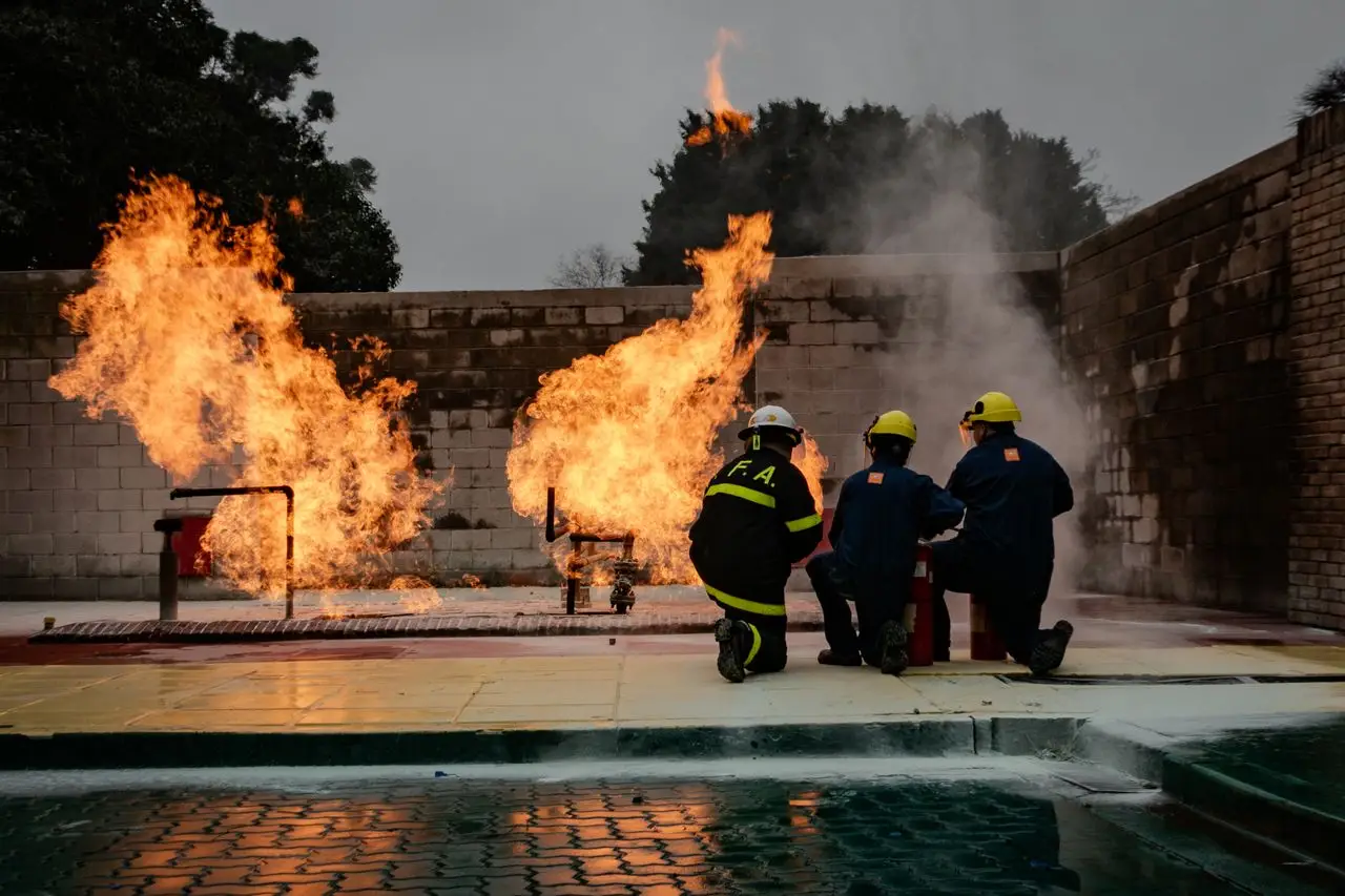 Firefighters in protective gear train with a controlled fire, focusing on safety and teamwork.